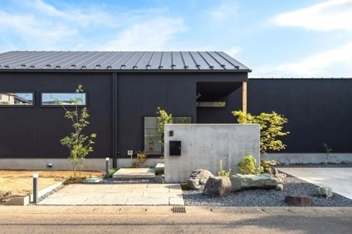 黒の外壁と屋根が植栽とマッチする平屋