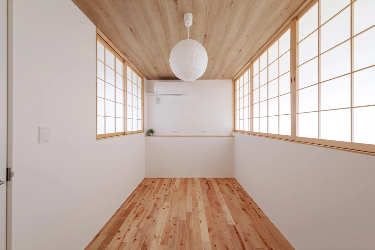 木目の天井と床に障子が調和する和モダンな室内と、中央に吊るされた白い丸い照明