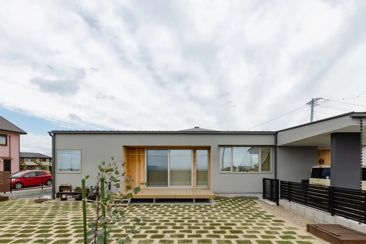 格子状の芝生が広がる庭とウッドデッキのある平屋の外観