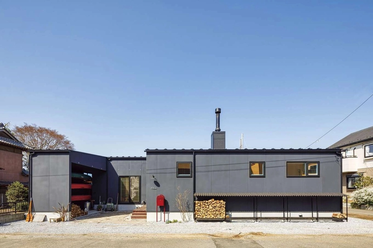 煙突と赤いポストがアクセントの黒い外壁のモダンな平屋