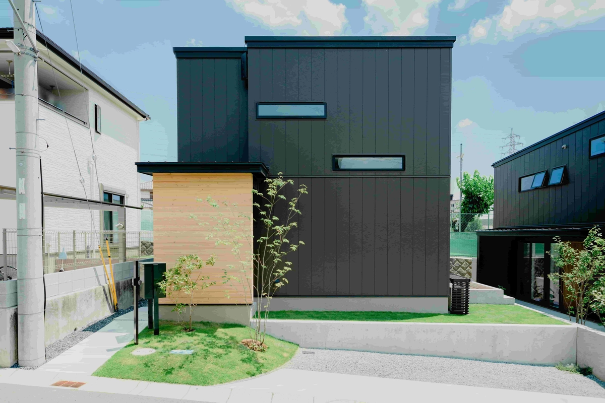 黒いガルバリウム鋼板の外壁と芝生の庭