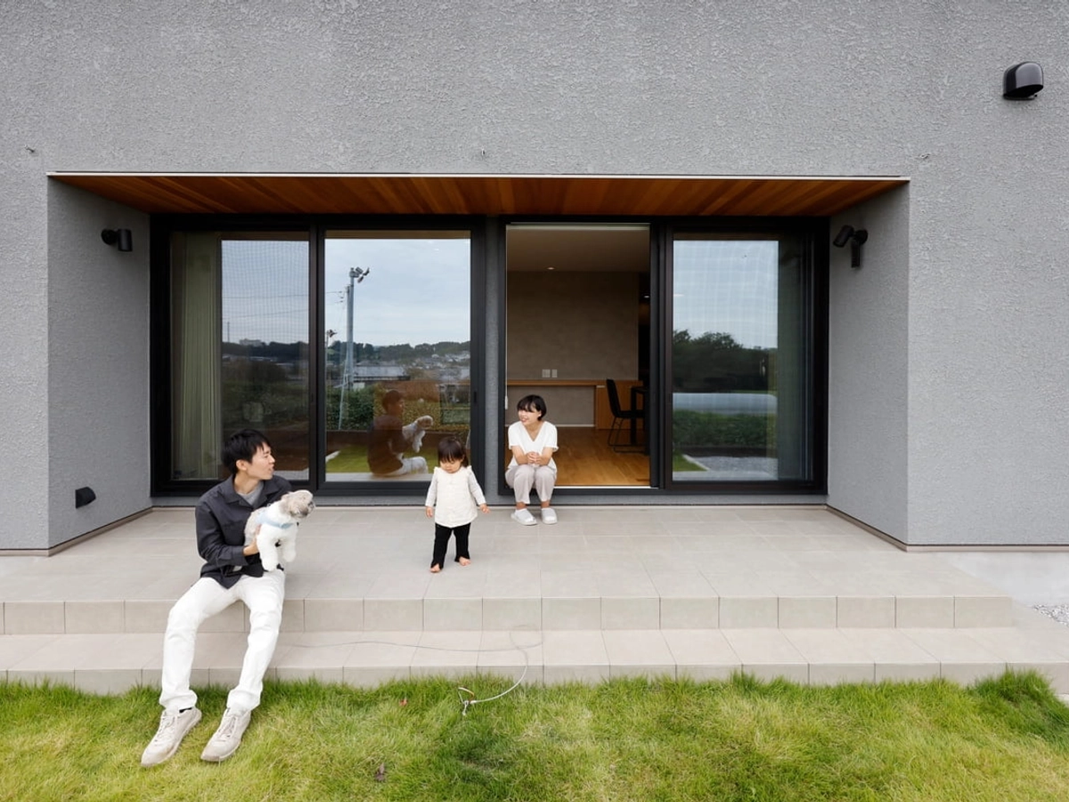 大きな窓から庭へ出て楽しげな様子の親子3人と愛犬