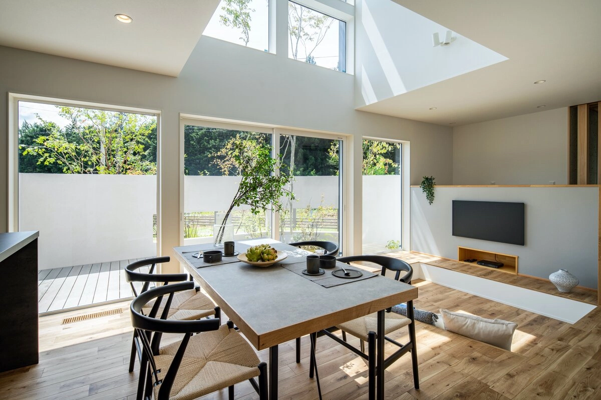 大きな吹き抜けから光が降り注ぐ、開放的でモダンなダイニングキッチンとリビング