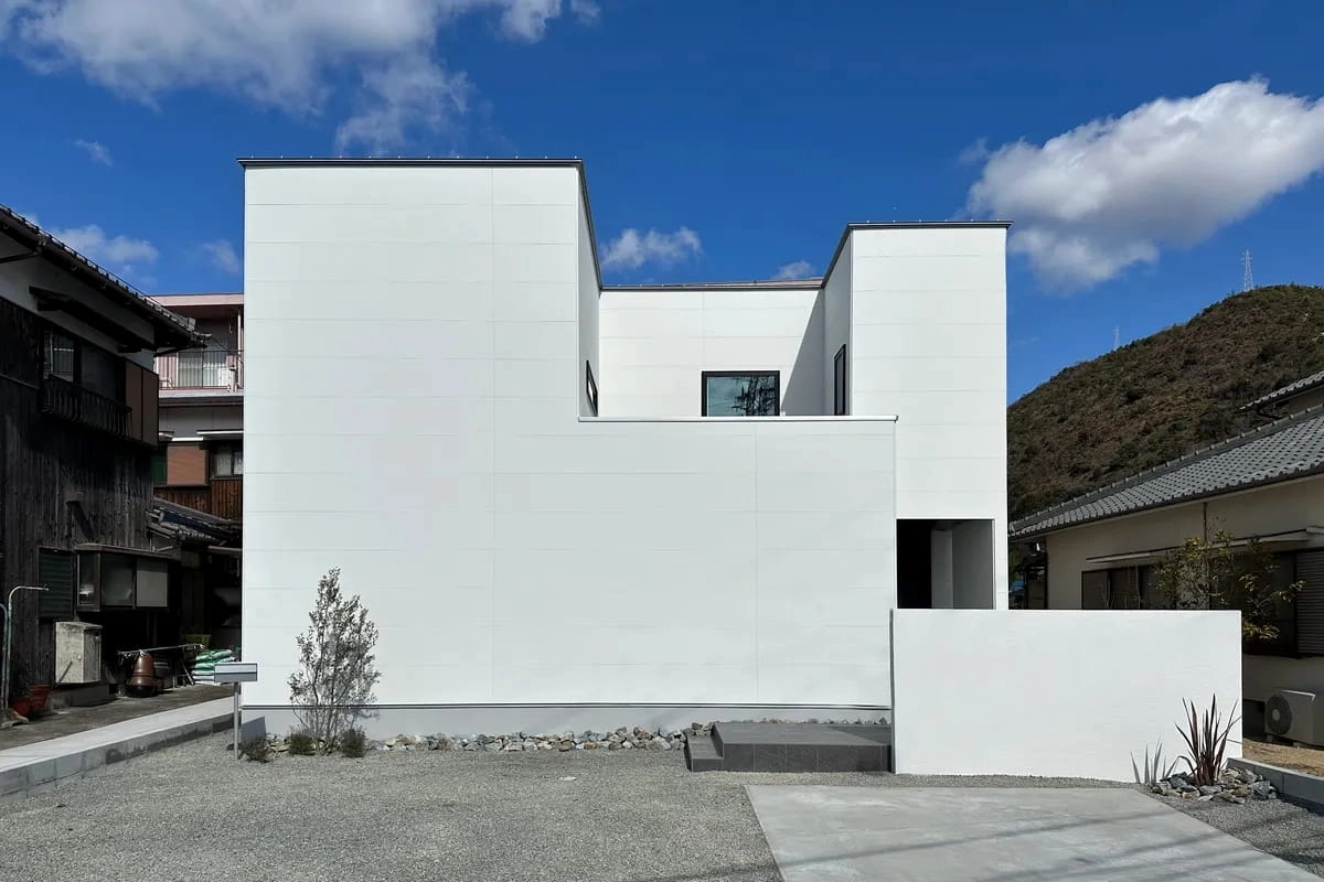 青空に映える凹凸のある白い箱型のモダンな住宅