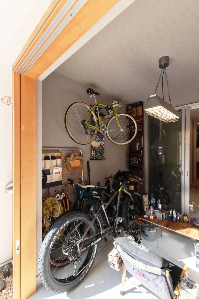 自転車の壁掛け収納やアウトドア用品が並ぶ土間空間