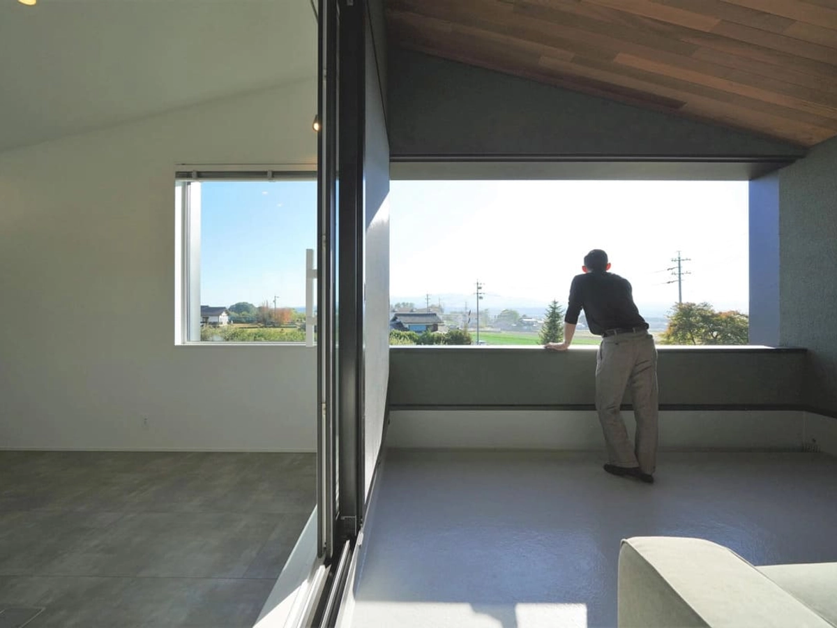 リビングの隣に設けたインナーバルコニーから景色を楽しむ男性