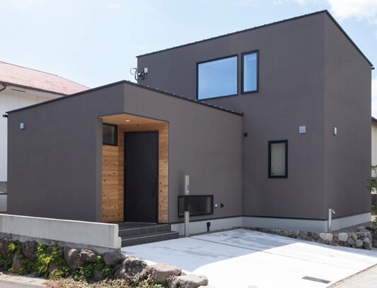 木材のアクセントがあるブラウンの箱型住宅の外観