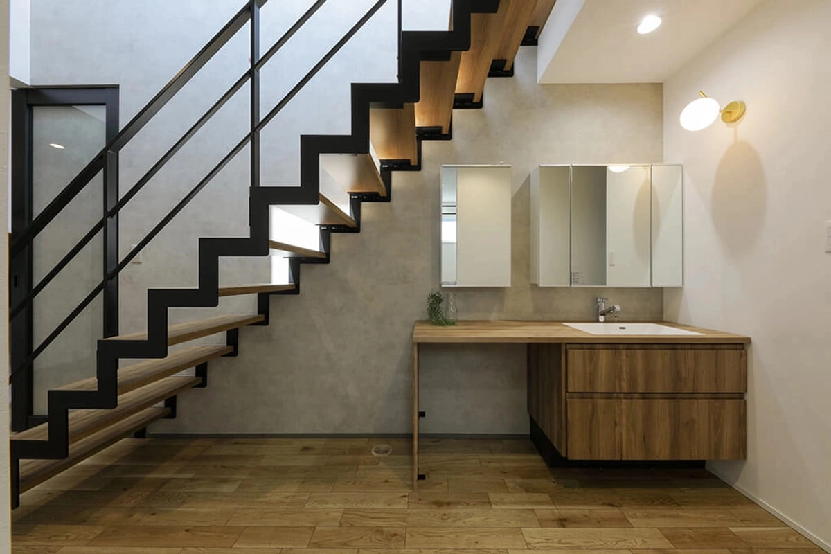 階段下に設けられた木製カウンターの洗面台と鉄骨階段