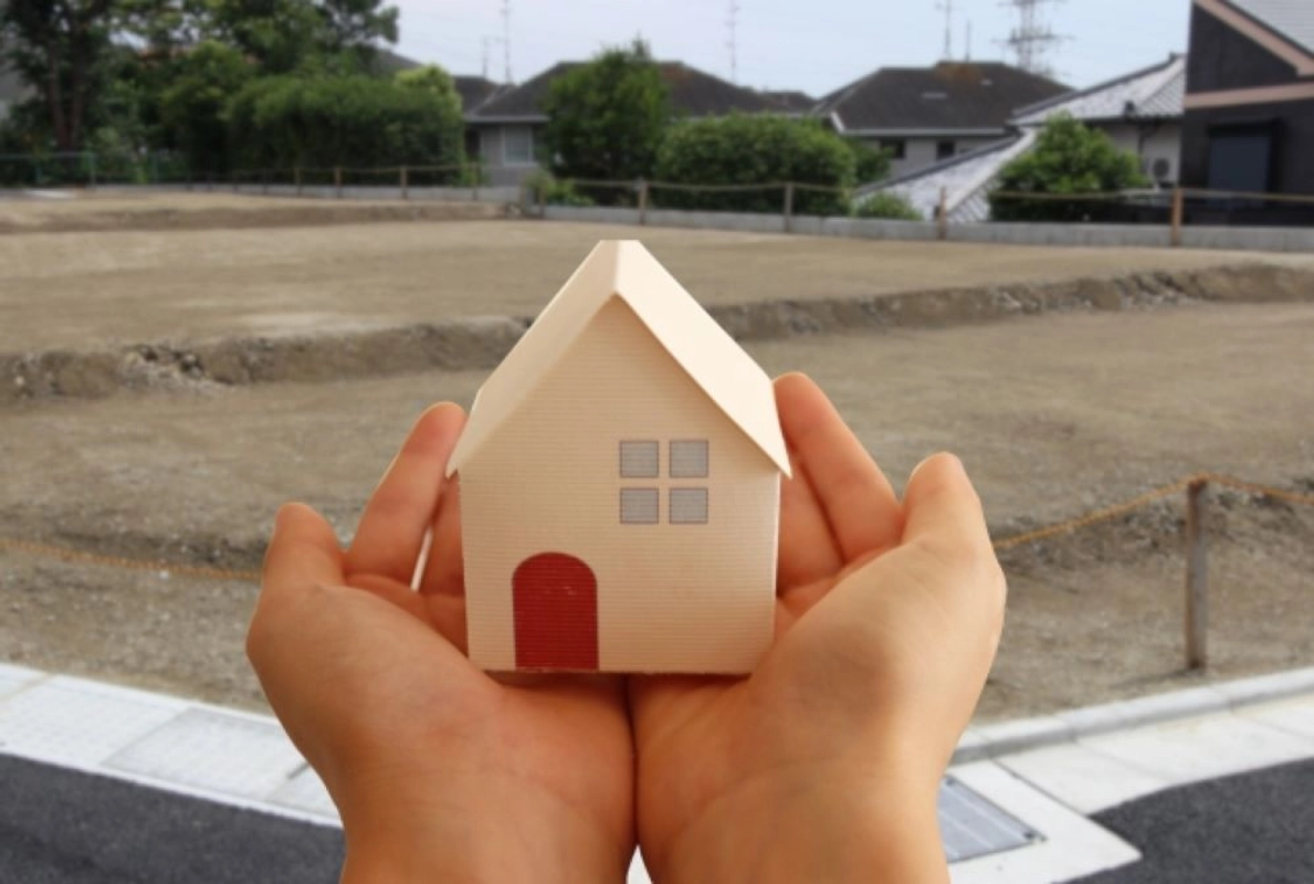 売地と手のひらに乗せた住宅模型