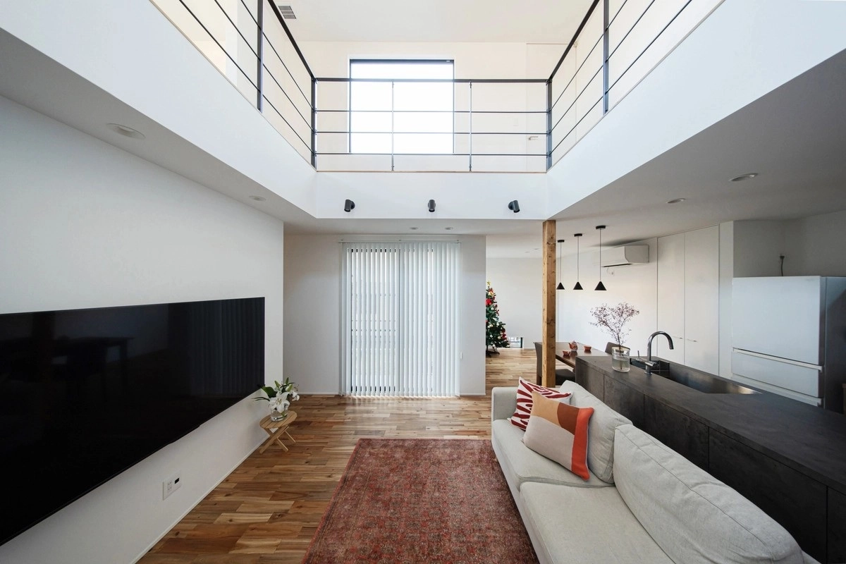 吹き抜けのある広々としたリビングとグレーのソファ