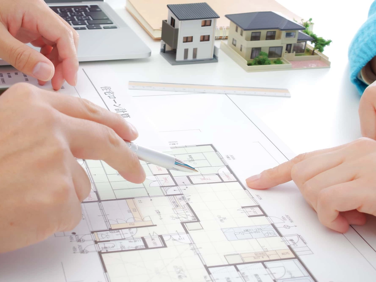 マイホームの間取りについて図面の上で話し合いをする男女の手元
