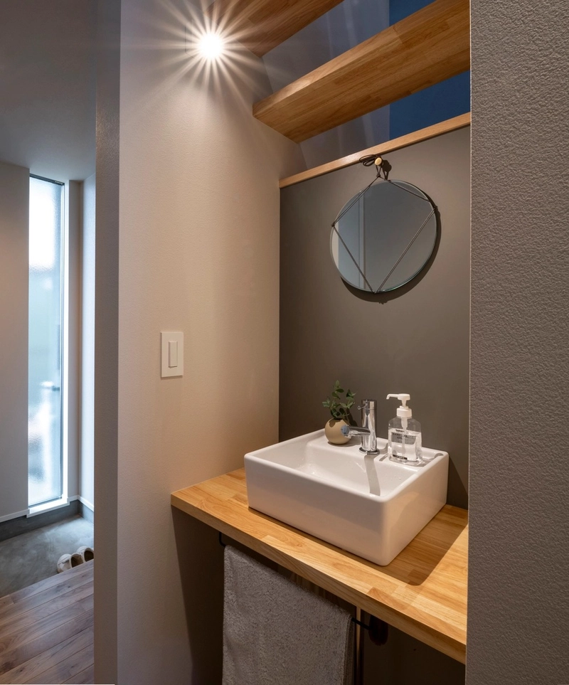 木製カウンターと丸鏡を組み合わせた温かみのある洗面コーナー
