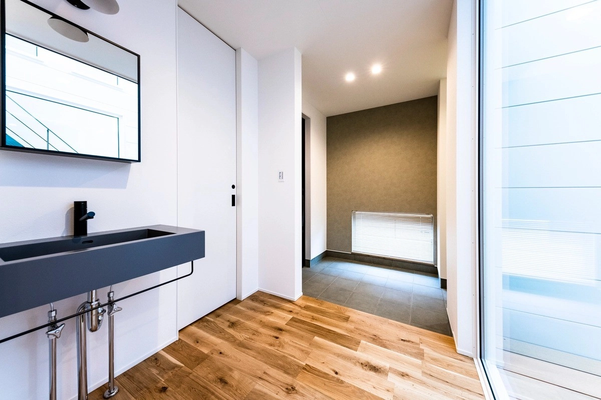 黒いスリムな洗面ボウルが目を引くスタイリッシュな玄関廊下