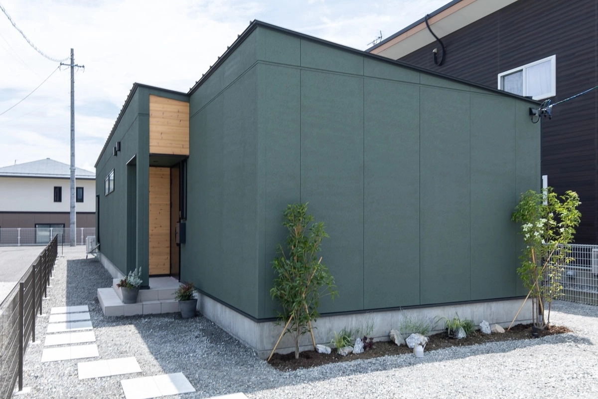 モスグリーンの外壁に木目のアクセントが映える平屋の外観