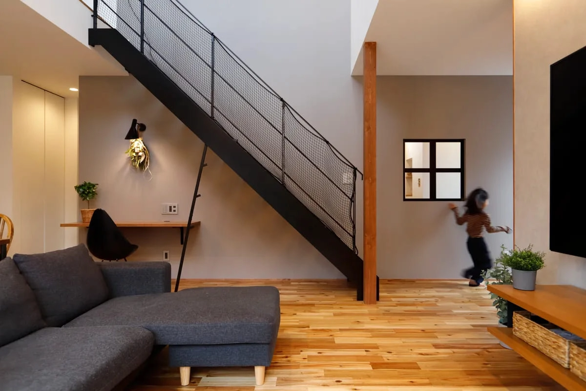 落下防止ネットが張られた鉄骨階段とリビング空間