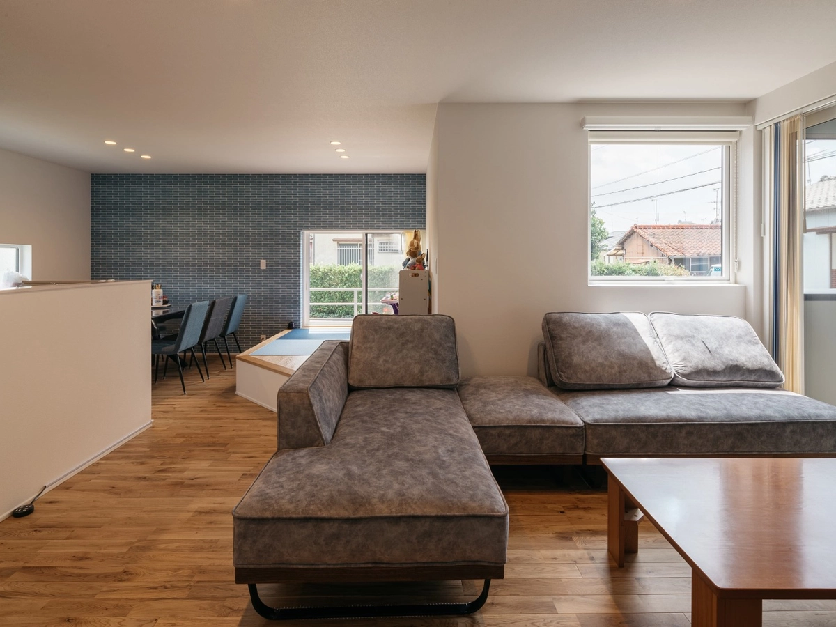 ブルーの壁がアクセントのグレーのソファーがあるLDK