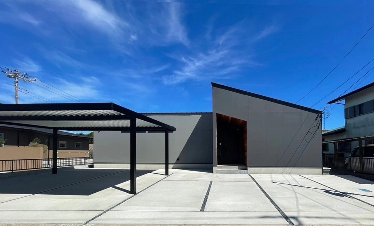 青空に映える片流れ屋根のグレーの外壁と広いカースペース