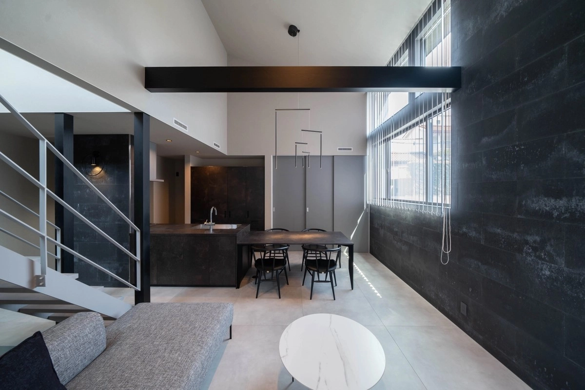 黒い石目調の壁面と吹き抜けが織りなす洗練されたホテルライクなLDKのインテリア