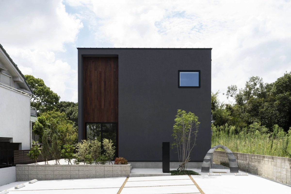 黒い外壁に木目調のアクセントと小窓が映えるモダンでスクエアな外観