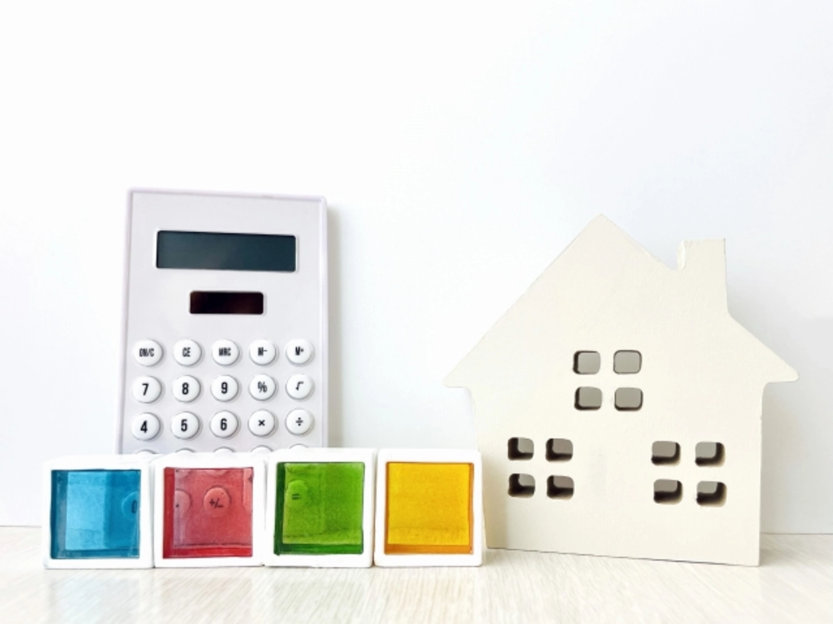 家の模型と電卓の前のブロック