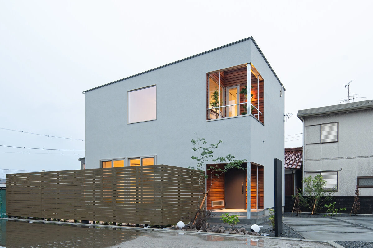 夕暮れ時に木目壁が映えるモダンなグレーのスクエア住宅