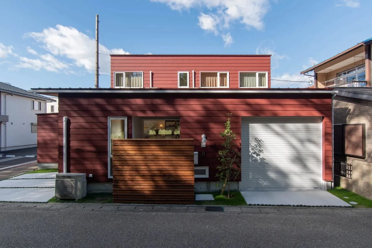 ビルトインガレージと木製フェンスがある赤茶色の住宅