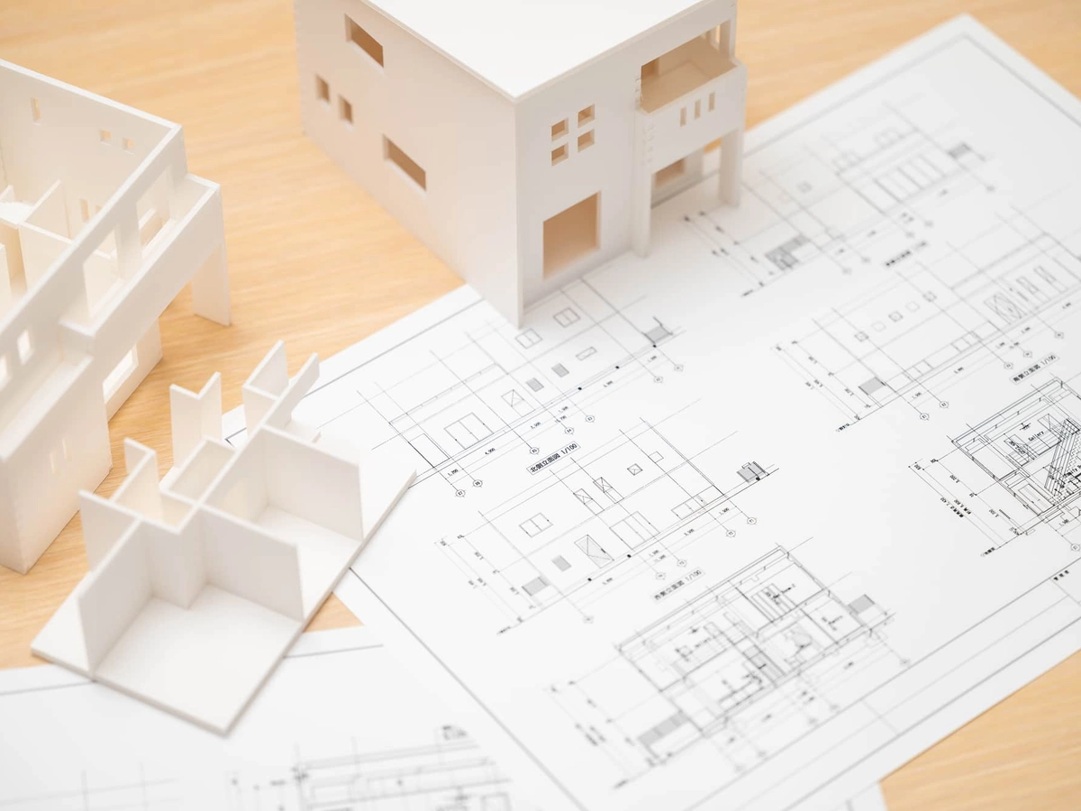 机の上に置かれた設計図面と住宅模型
