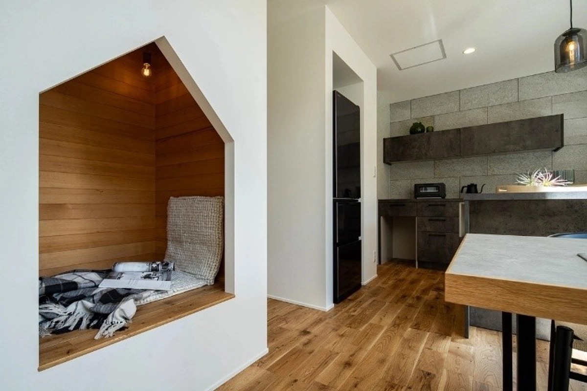壁を家型にくり抜いた木のヌックスペースと、奥に見えるシックなグレーのキッチン