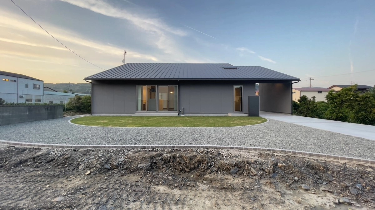 芝生の庭と砂利が美しく整備された、落ち着いたグレーの外壁の平屋