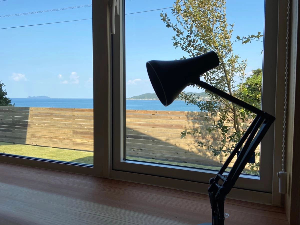 デスクライトの置かれたワークスペースと窓から見える海