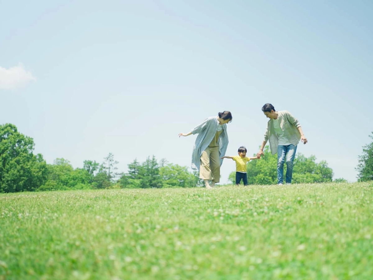 緑の丘で遊びまわる家族