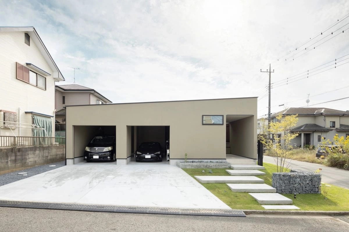 2台分のガレージとコンクリートステップがあるベージュの住宅