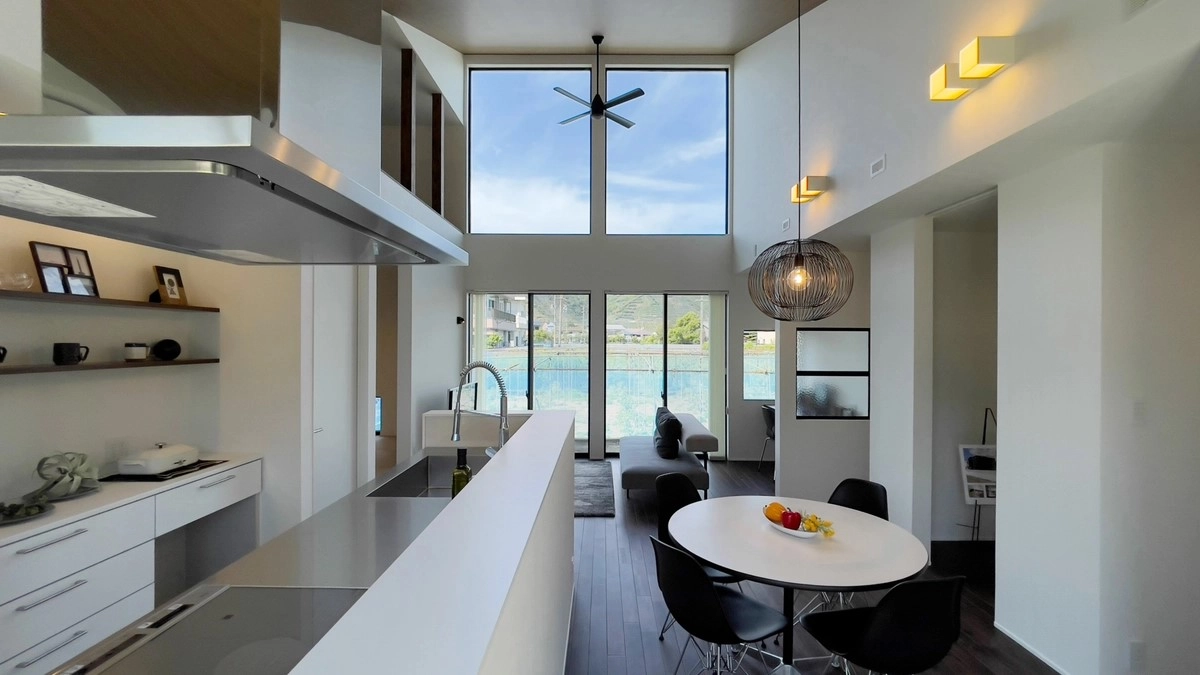 高い吹き抜けと大きな窓から空が見える開放的なアイランドキッチン