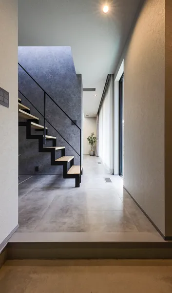 空へ抜けるグレーの家の玄関・階段