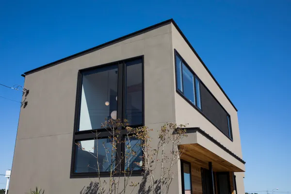 風景と重なる大きな窓の家の外観