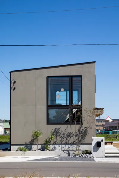 風景と重なる大きな窓の家の外観