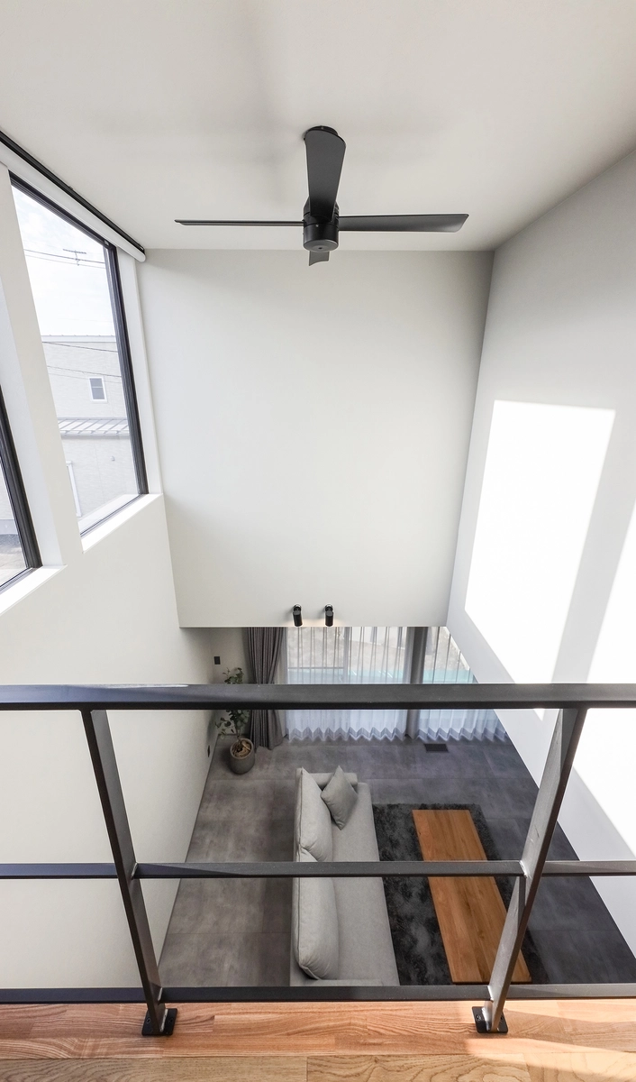 空へ抜けるグレーの家の吹き抜け